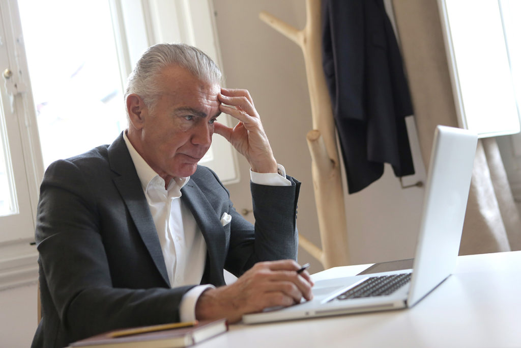 A man in a suit sitting at a desk with a laptop.